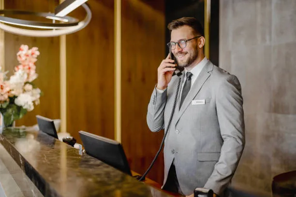 Hombre con traje en la recepción de un hotel haciendo una llamada, mostrando cómo el software para hoteles optimiza la atención al cliente y la gestión.