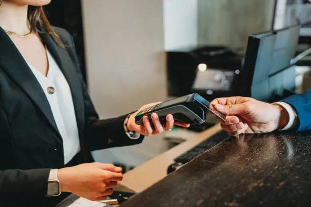 Recepción de hotel con terminal para aceptar pagos con tarjeta, ideal para ofrecer opciones de pago seguras y rápidas, cumpliendo estándares de seguridad en pasarelas de pago