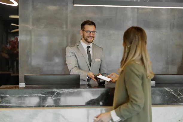 Recepcionista dándole la llave electrónica a una clienta, demostrando la eficiencia de un sistema hotelero moderno en la gestión de servicios.