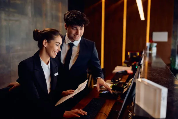 Dos recepcionistas usando una computadora para gestionar reservas y operaciones de un hotel con un pms hotel.