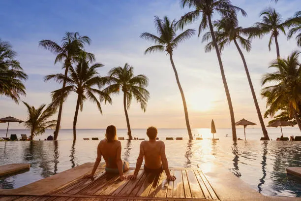 Una pareja disfrutando la playa mientras el hotel gestiona eficientemente sus servicios mediante un programa gestión hotelera.