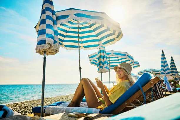 Mujer en la playa disfrutando de sus vacaciones mientras el hotel gestiona reservas y servicios con un pms hotel.