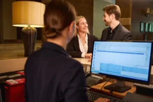 Una recepcionista de hotel que se encuentra aprovechando las ventajas de usar un software hotelero registrando sus clientes.