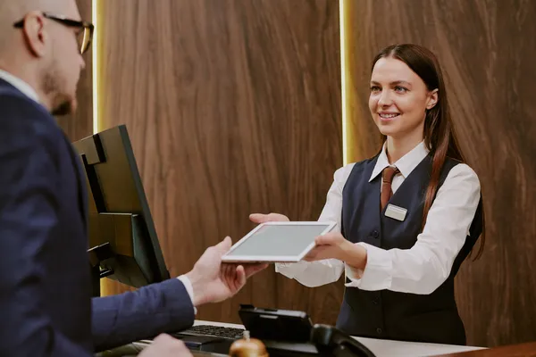 Imagen en donde se puede ver a una mujer como una recepcionista que aprovecha las funciones de un sistema de control hotelero.