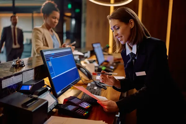 Una recepcionista otorgando un servicio de calidad a todos los huéspedes gracias a un sistema de reservaciones para hoteles.
