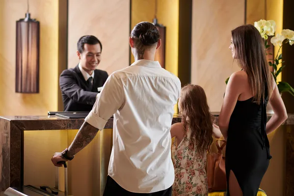 Familia haciendo registro de entrada de manera eficaz gracias a la implementación de un sistema de reservaciones para hoteles.