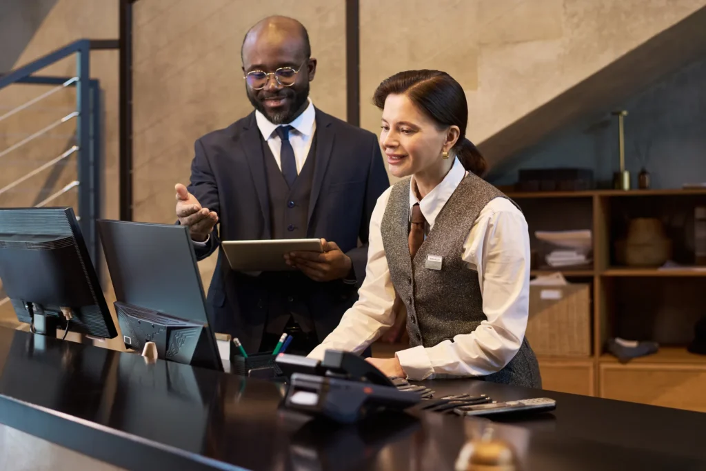Gerente y recepcionista hablando sobre el ERP vs sistema contable tradicional ¿Qué le conviene a tu hotel?