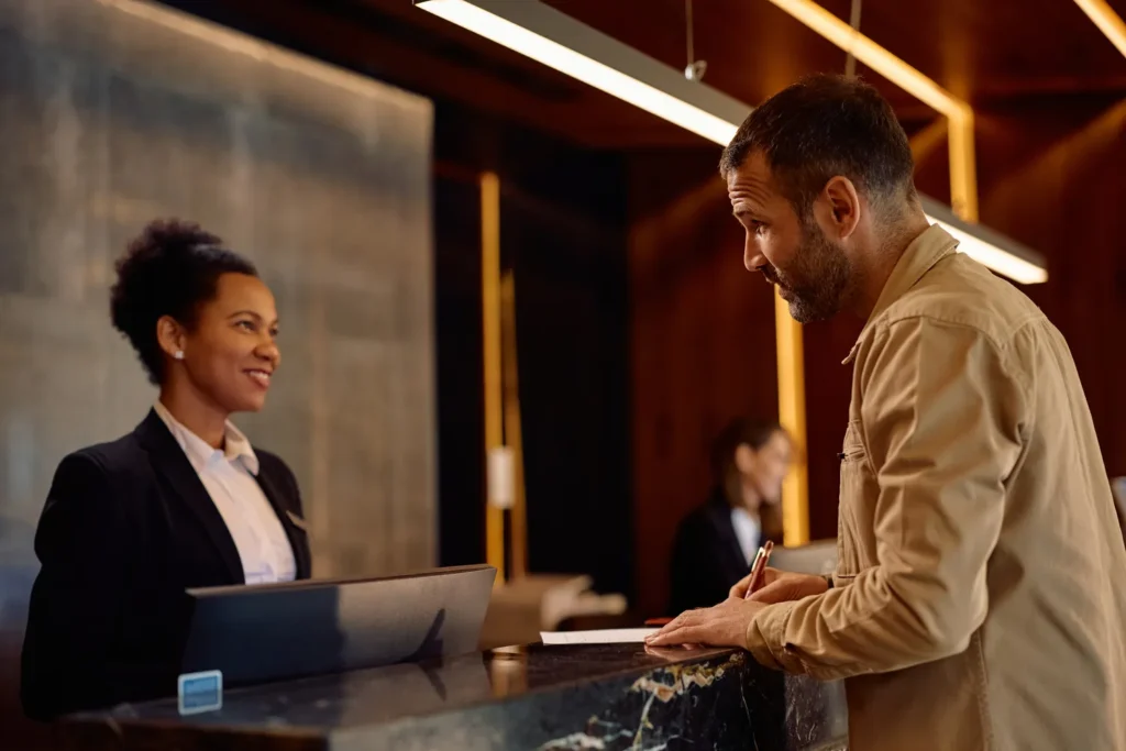 Fotografía de la recepción donde un turista y una gerente hablan sobre ERP vs sistema contable tradicional ¿Qué le conviene a tu hotel?