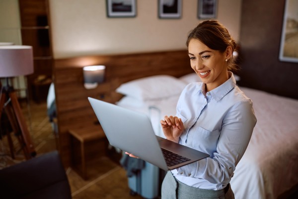 Foto de una mujer encargada de hotel con su laptop feliz ya que sabe qué es un motor de reservas