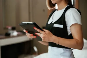 Foto a una ama de llaves en hoteles usando una tablet para optimizar el servicio e informar la disponibilidad del cuarto.