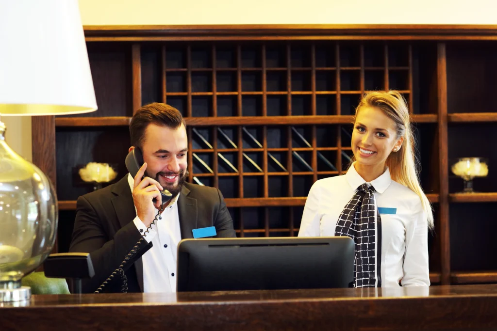 Foto de un gerente y recepcionista de hotel que cuenta con un avanzado sistema PMS para hotel que lo moderniza al instante