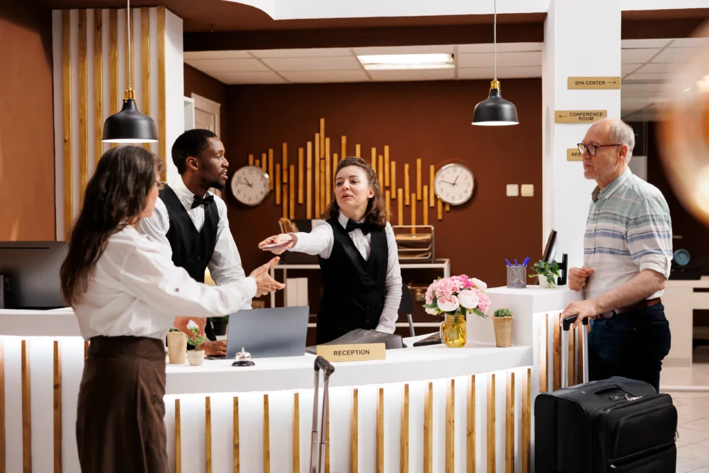 Fotografía de huéspedes conversando con recepcionistas de un hotel que cuenta con sistema PMS para hotel
