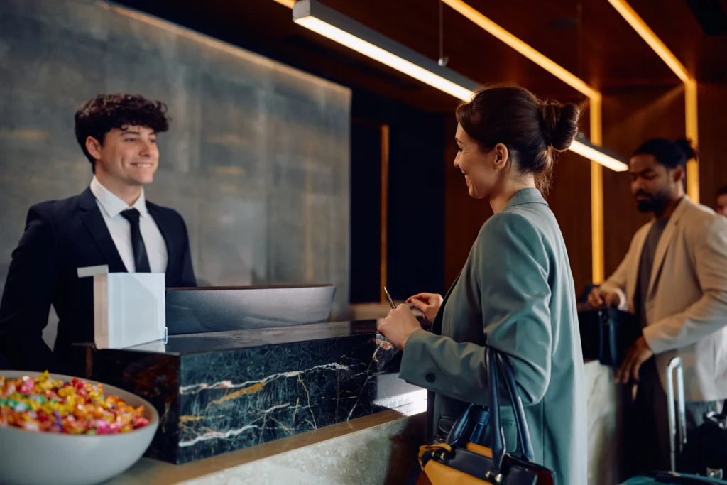 Fotografía de un joven recepcionista feliz realizando el Self check-in en hoteles de su huésped