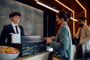 Fotografía de un joven recepcionista feliz realizando el Self check-in en hoteles de su huésped