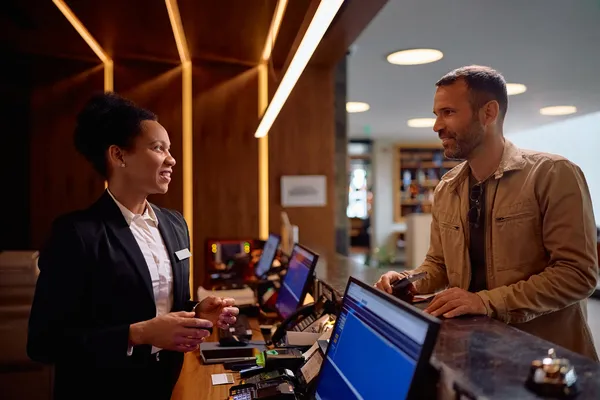 Foto de mujer atendiendo a huésped que visita un hotel con software hotelero para hoteles pequeños y hostales
